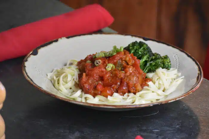 A close up of a pasta dish with a side of broccoli.