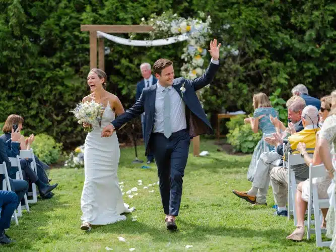 Couple recently married walks down the aisle together in the Orchard Garden at basin harbor