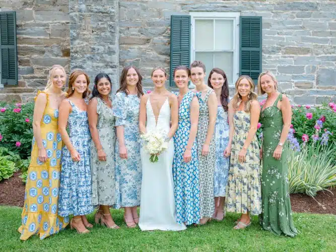 Bridal party in color floral dresses with bride in front of Historic Homestead at Basin Harbor