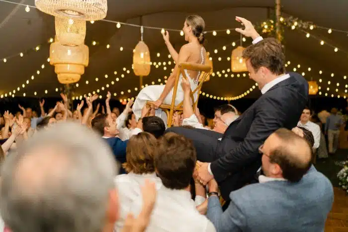 Tented wedding with group dancing under twinkle lights.