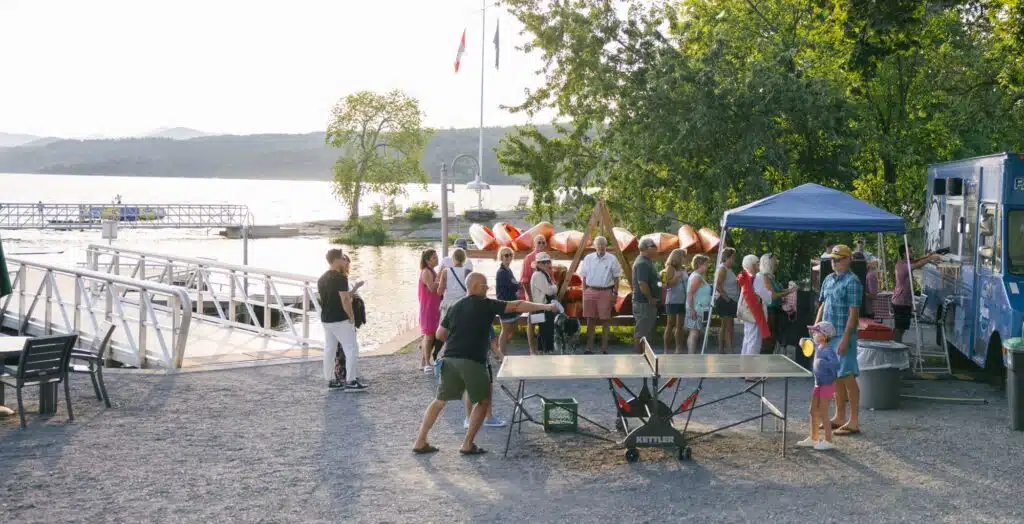 A group of people waiting in line at the food truck by the dock.