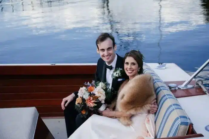 A bride and groom riding in the back of a boat.