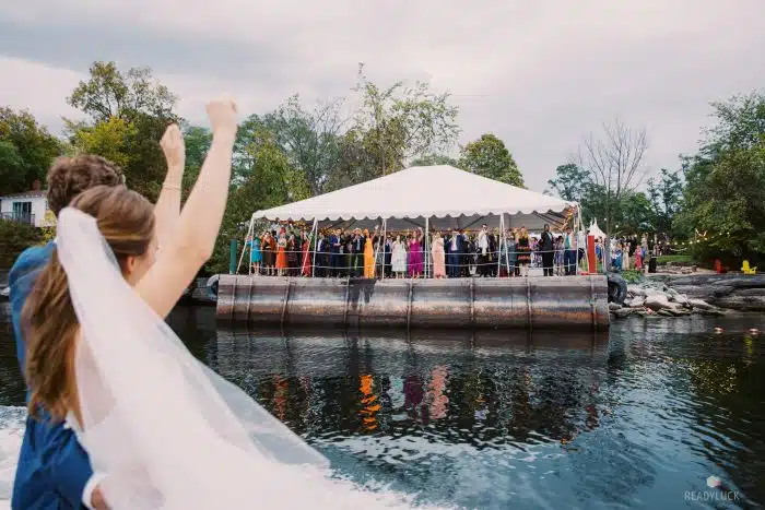 A couple waving goodbye to their wedding reception from a boat