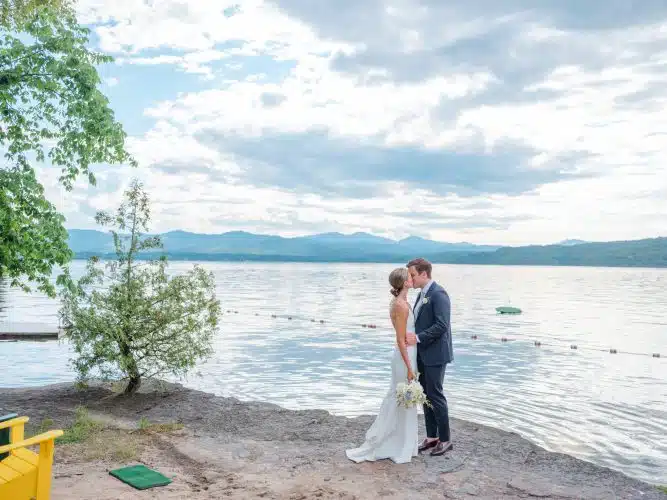 A bride and groom kissing by the lake