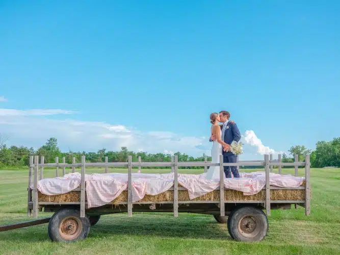 A bride and groom kissing on a hay ride