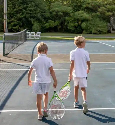 Brothers walking on a tennis court with tennis racquets