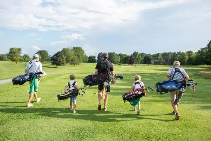A family walking on the golf course with golf equipment