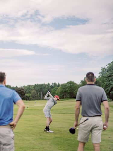 Golf at Basin Harbor. Man takes a swing off a green.