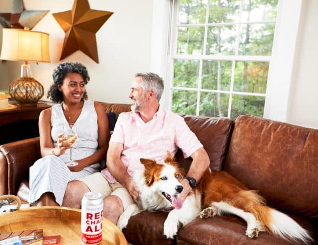 A couple sitting on a couch with their dog