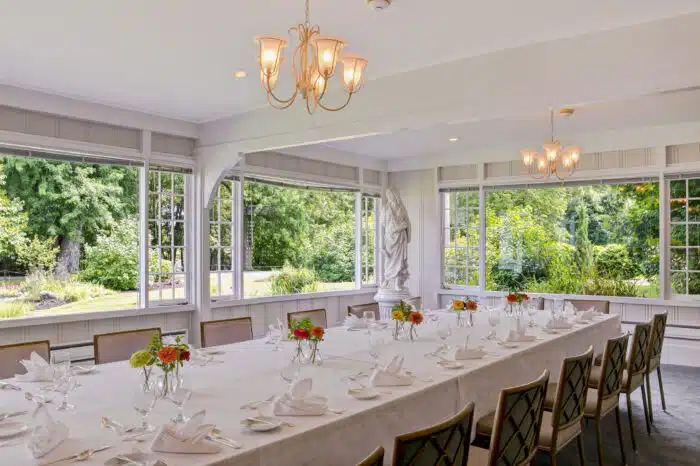 Family style table with cheerful flower arrangements in the Garden Room in Ardelia's venue