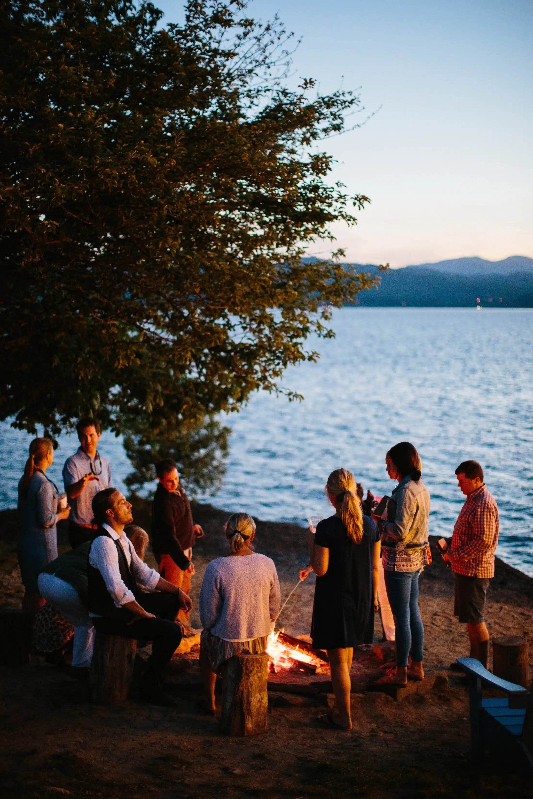 A group of people roasting marshmallows around a campfire