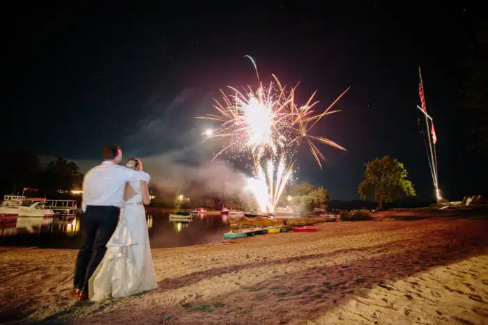 A bride and groom watching fireworks on the beach