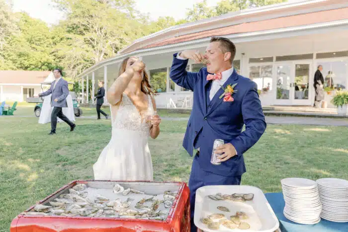 Wedding couple shot oysters from their raw bar on the Lodge Lawn