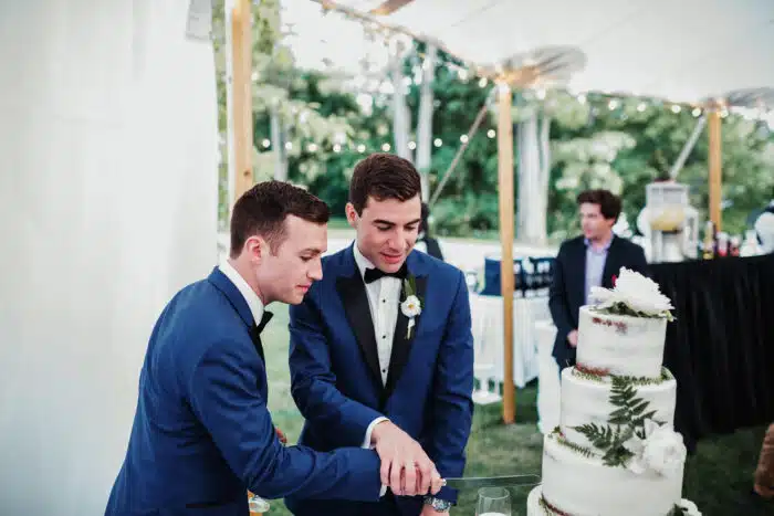 Two grooms cutting their wedding cake at their wedding reception
