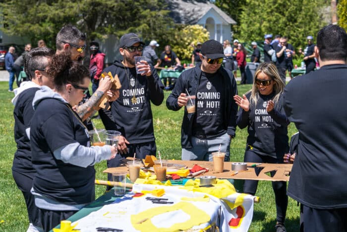 Groups gather around tables for a team building challenge.