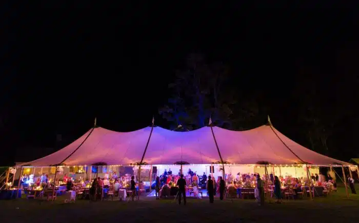 A wedding tent lit up by purple lights at during the reception